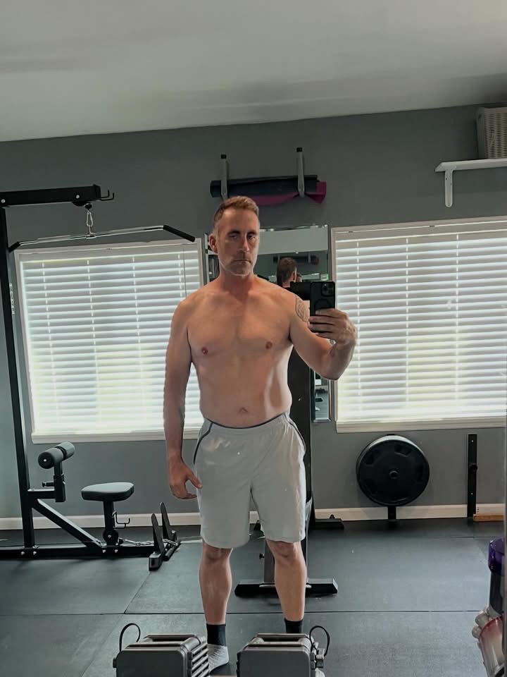 Brian’s starting photo, standing in his home gym wearing light shorts