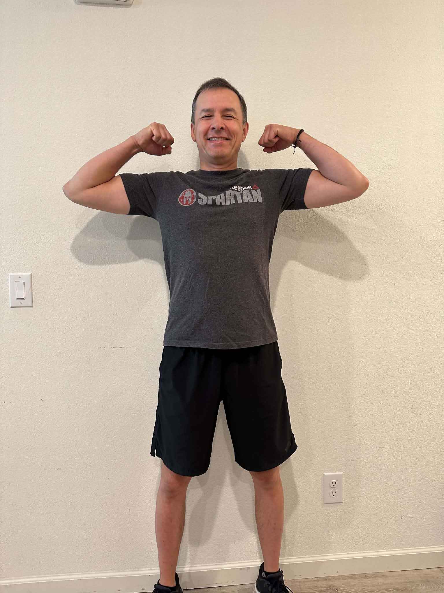 Ed after coaching, flexing in a grey T-shirt and black shorts